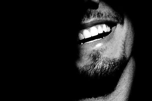 Sonrisa brillante en un rostro parcialmente en sombras.