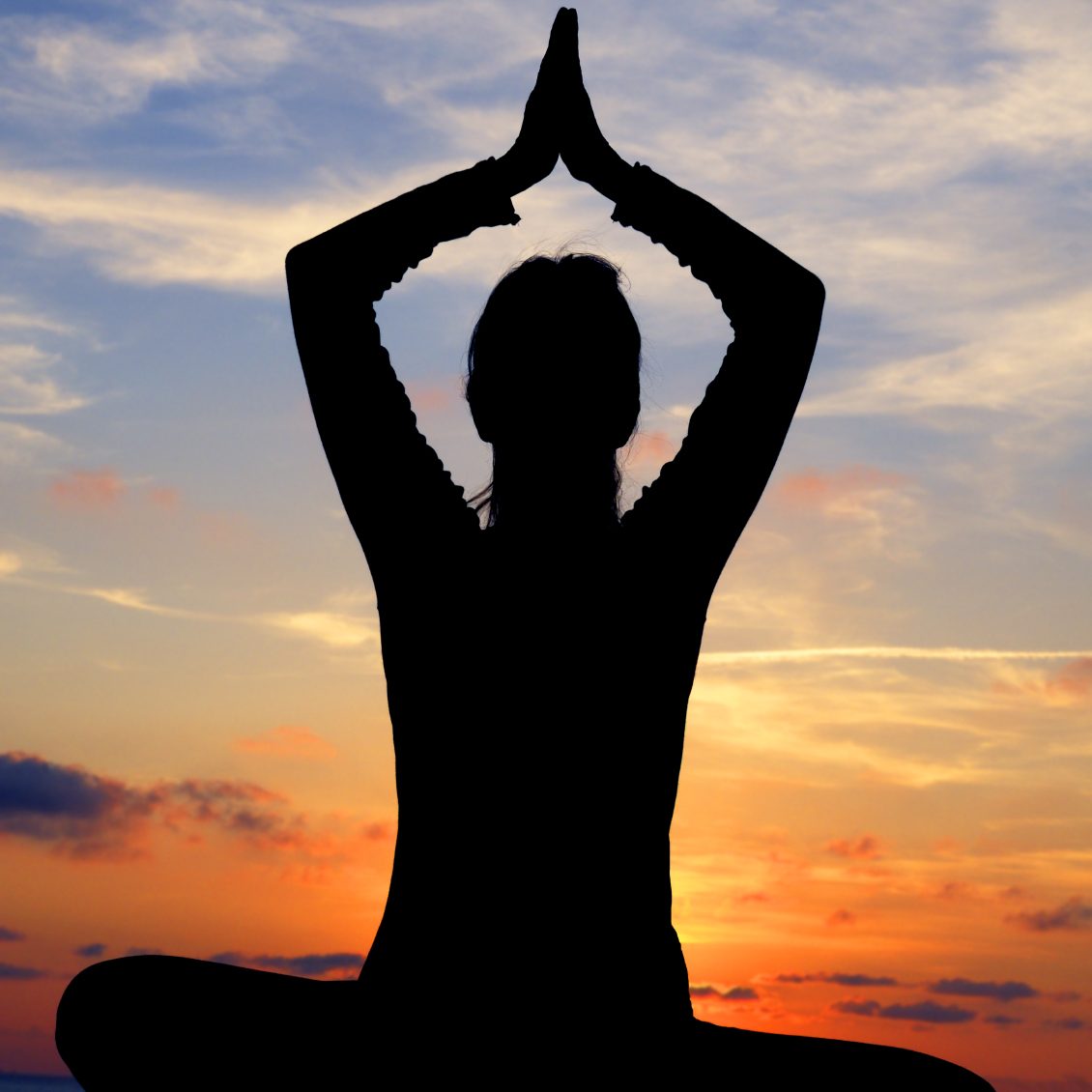Silhouette de una persona en postura de meditación al atardecer.
