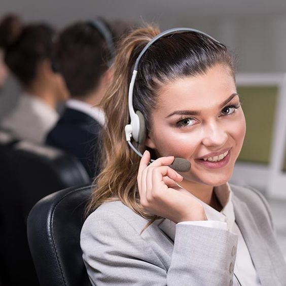 Mujer sonriente con auriculares en un ambiente de trabajo.