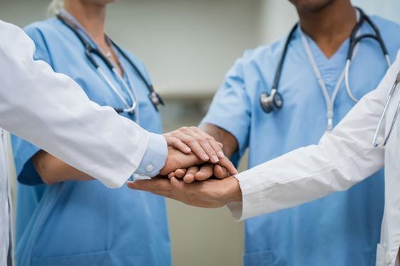 Manos de profesionales de la salud unidas en un gesto de colaboración y apoyo.