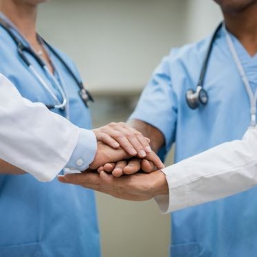 Manos de profesionales de la salud unidas en un gesto de apoyo y colaboración.